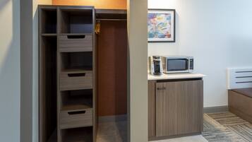 A modern kitchen with a built-in microwave, a wooden cabinet, and a small seating area.