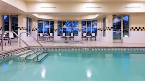 Un espace piscine offrant une vue dégagée sur le ciel grâce à de grandes fenêtres, une piscine dont le bord est revêtu de carreaux, ainsi que plusieurs chaises longues et tables.