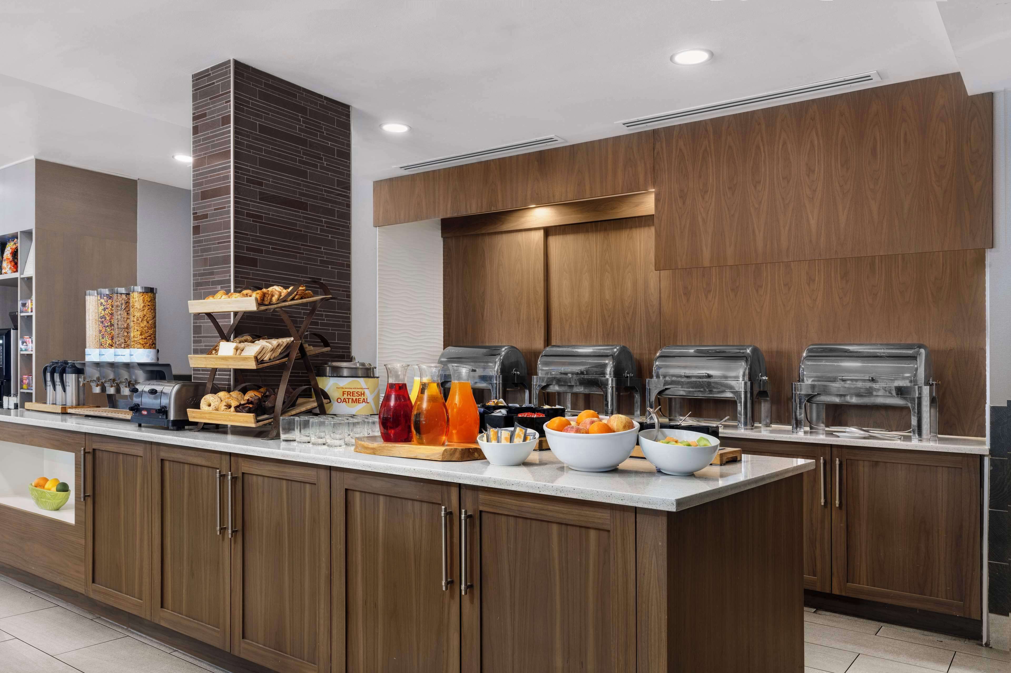A modern breakfast bar with self-serve coffee machines, a variety of fresh juices, and a selection of pastries.