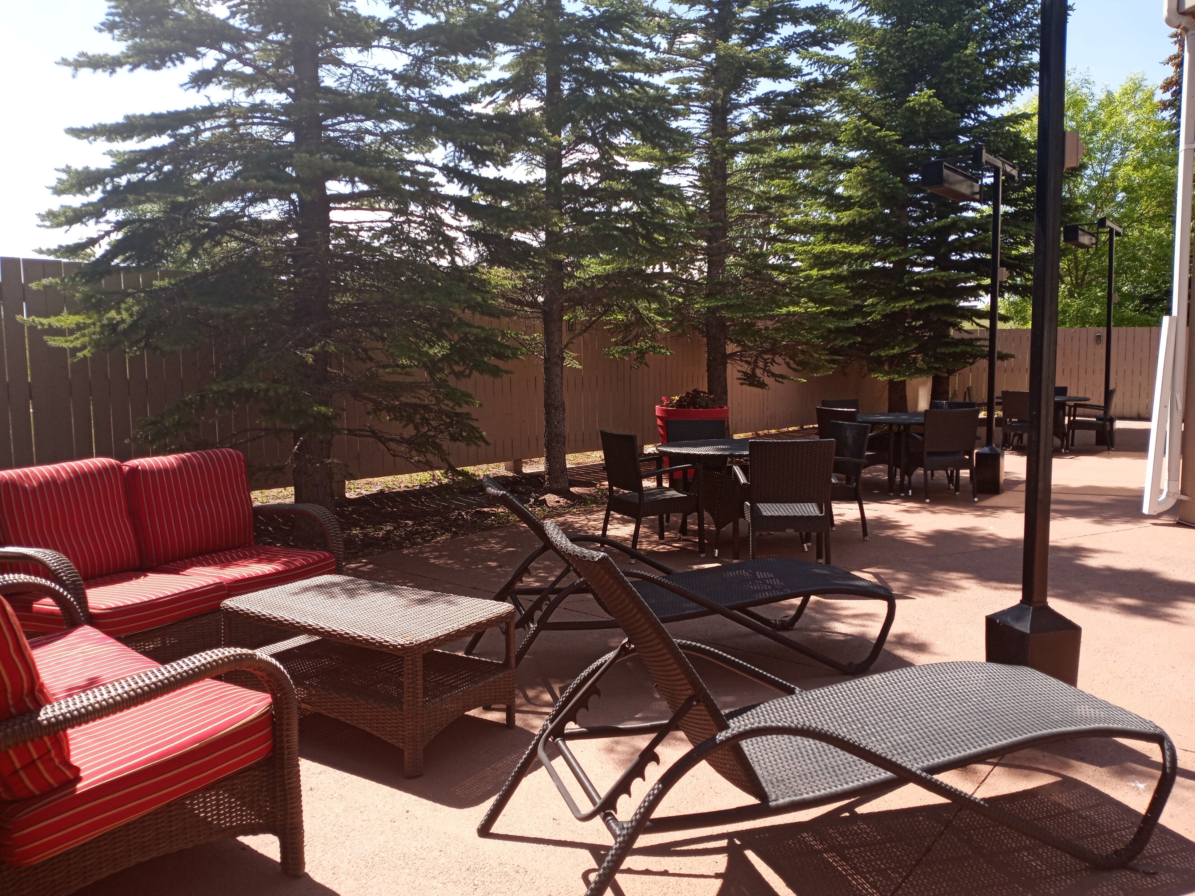 An outdoor patio with wicker furniture, a red sofa, and a dining table.