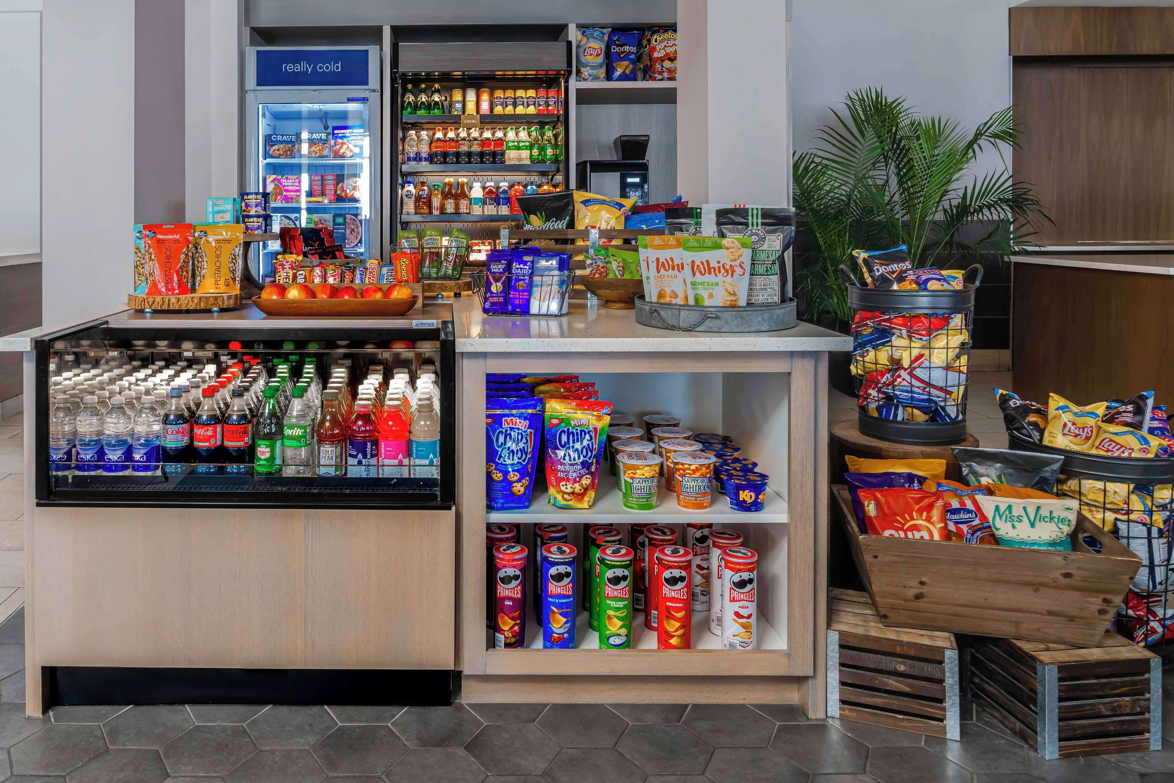 Una estación de autoservicio con bebidas y aperitivos, que incluye variedad de bebidas, bocadillos y papas fritas.
