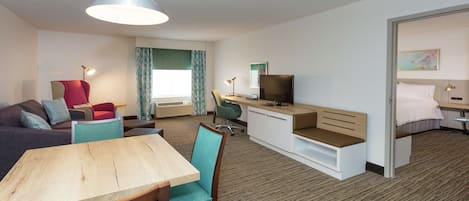 Ett modernt hotellrum med en matplats, en TV, ett skrivbord och en säng.