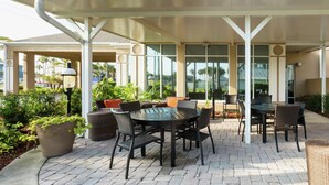 An outdoor patio with a covered seating area, a round table, and chairs. - Hilton Garden Inn St. Augustine Beach (St. Augustine)