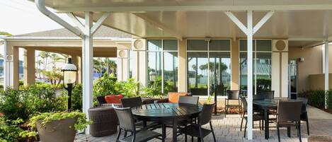 An outdoor patio with a covered seating area, a round table, and chairs.