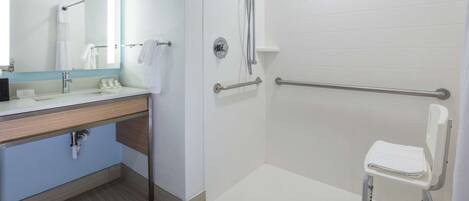 A modern bathroom with a shower, grab bars, a sink, and a toilet.