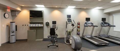 Une salle de sport équipée de tapis de course, d’un vélo elliptique, d’un vélo d’appartement et d’un banc de musculation.