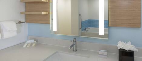 Un baño con un espejo grande, un lavabo y un perchero para toallas.