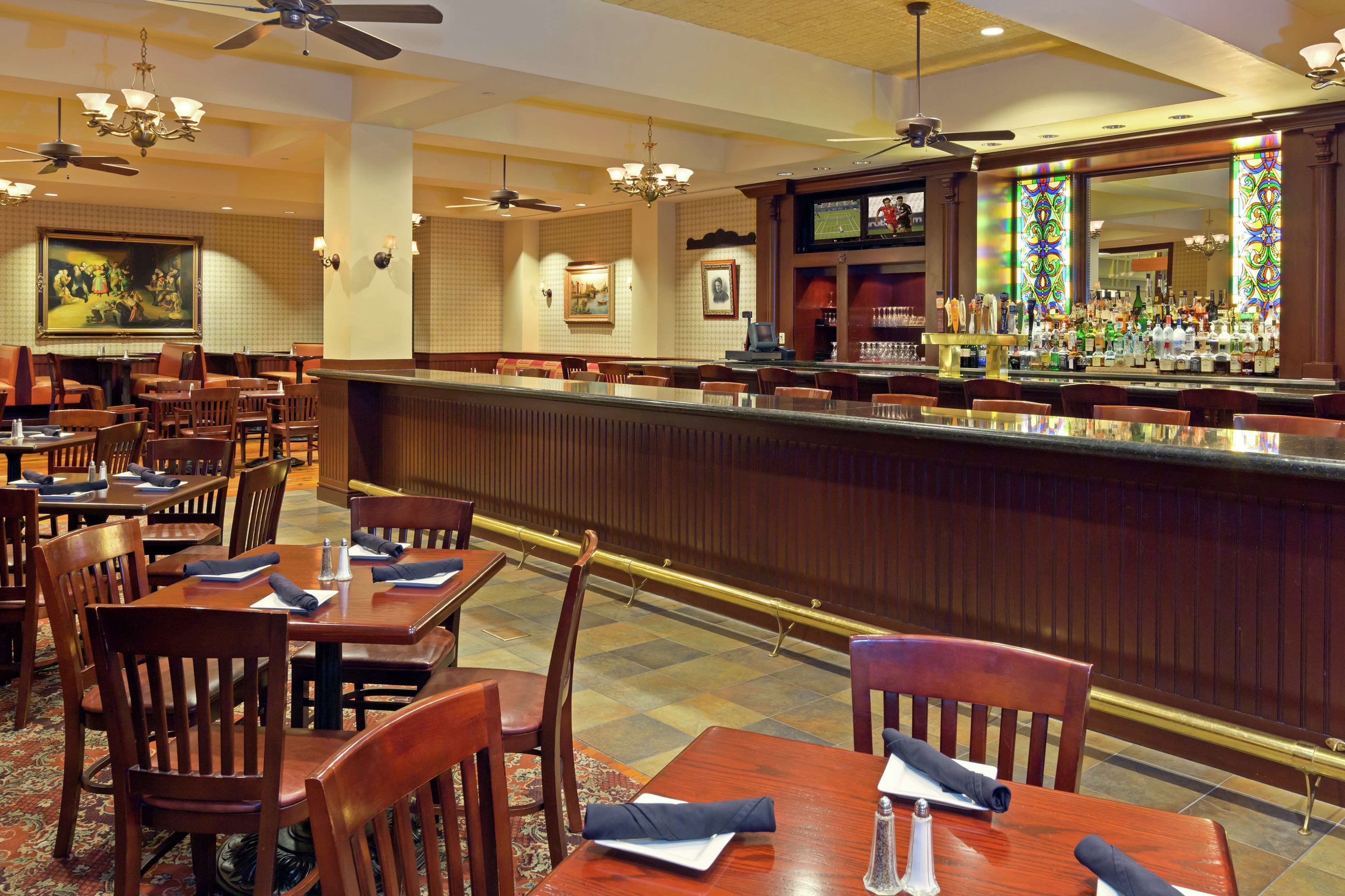 A restaurant with wooden tables and chairs, a bar area, and ceiling fans.