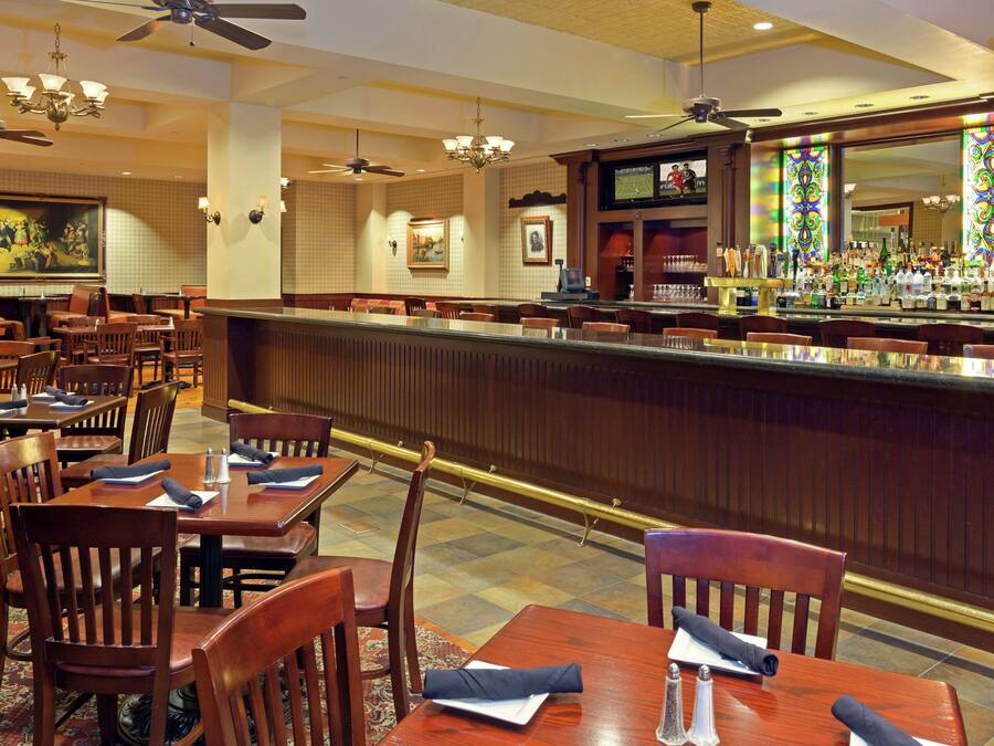 A restaurant with wooden tables and chairs, a bar area, and ceiling fans.