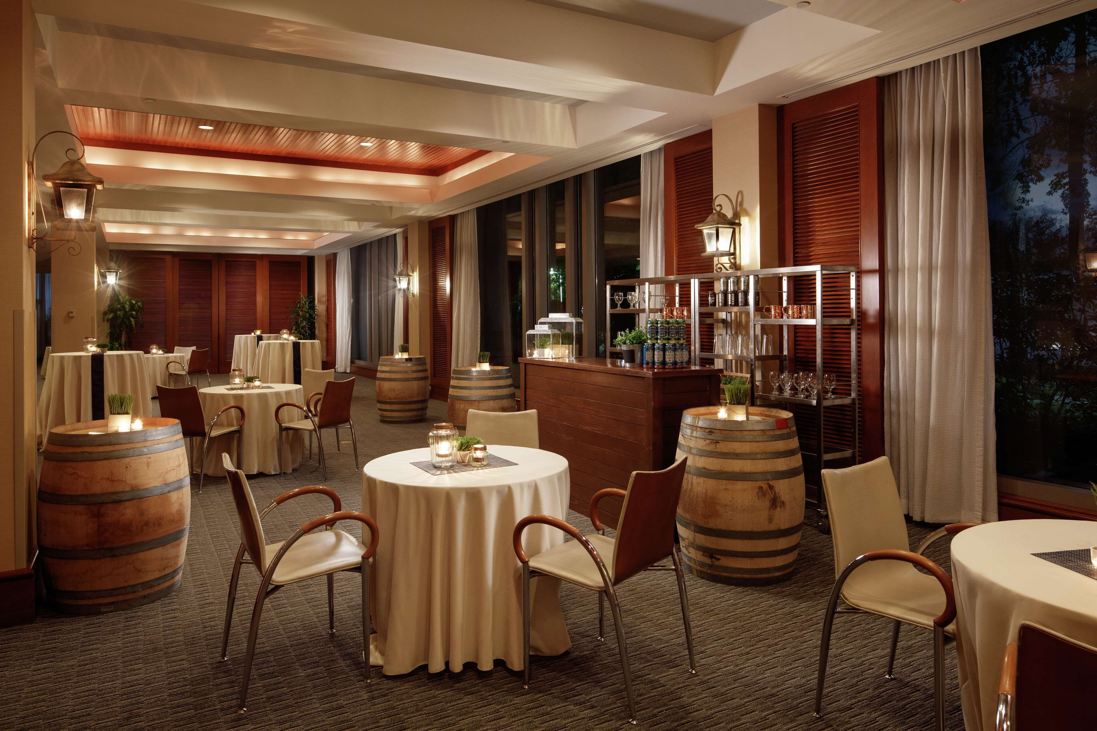 Un restaurant avec des tables rondes, des tonneaux en bois et un coin bar.