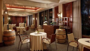 Un restaurant avec des tables rondes, des tonneaux en bois et un coin bar.