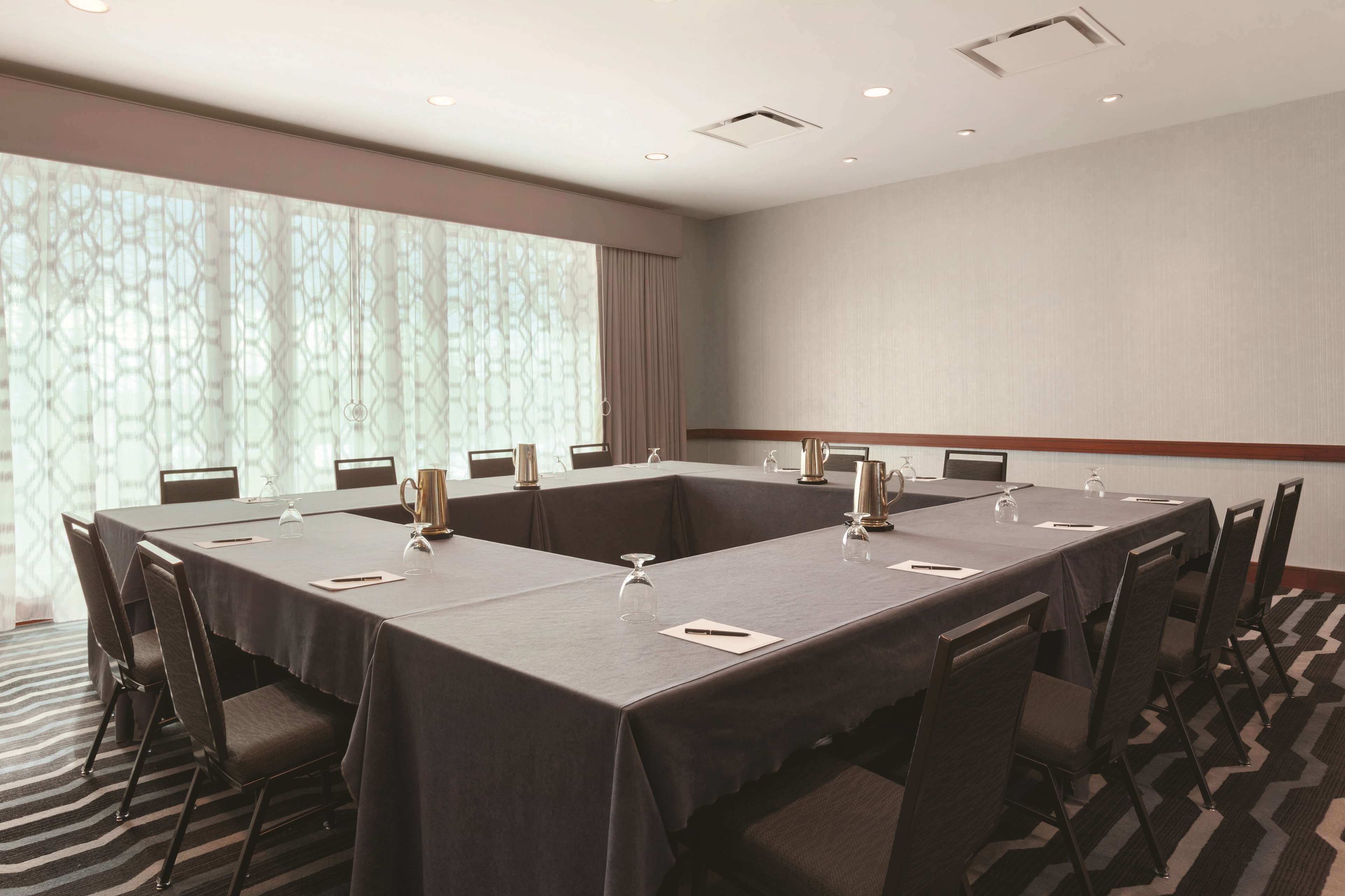 A conference room with a long table, chairs, and a patterned window view.