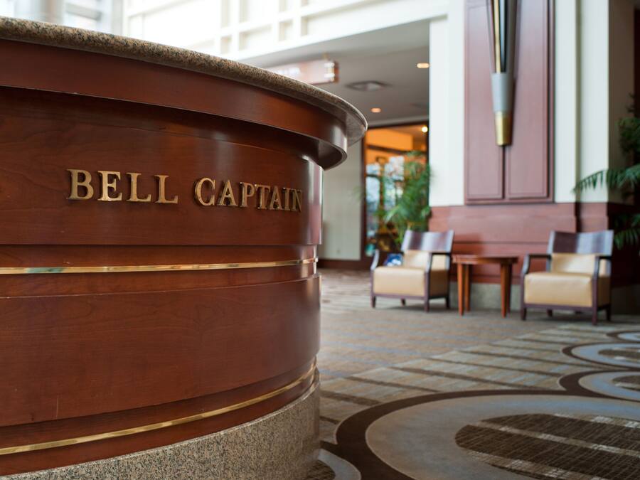 En receptionsdisk i trä med inskriptionen ”BELL CAPTAIN” i en hotellobby.