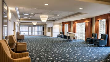 A spacious room with a patterned carpet, a grand piano, and several chairs.