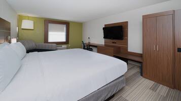 Una habitación de hotel con una cama grande, un escritorio con silla, un televisor y un armario.
