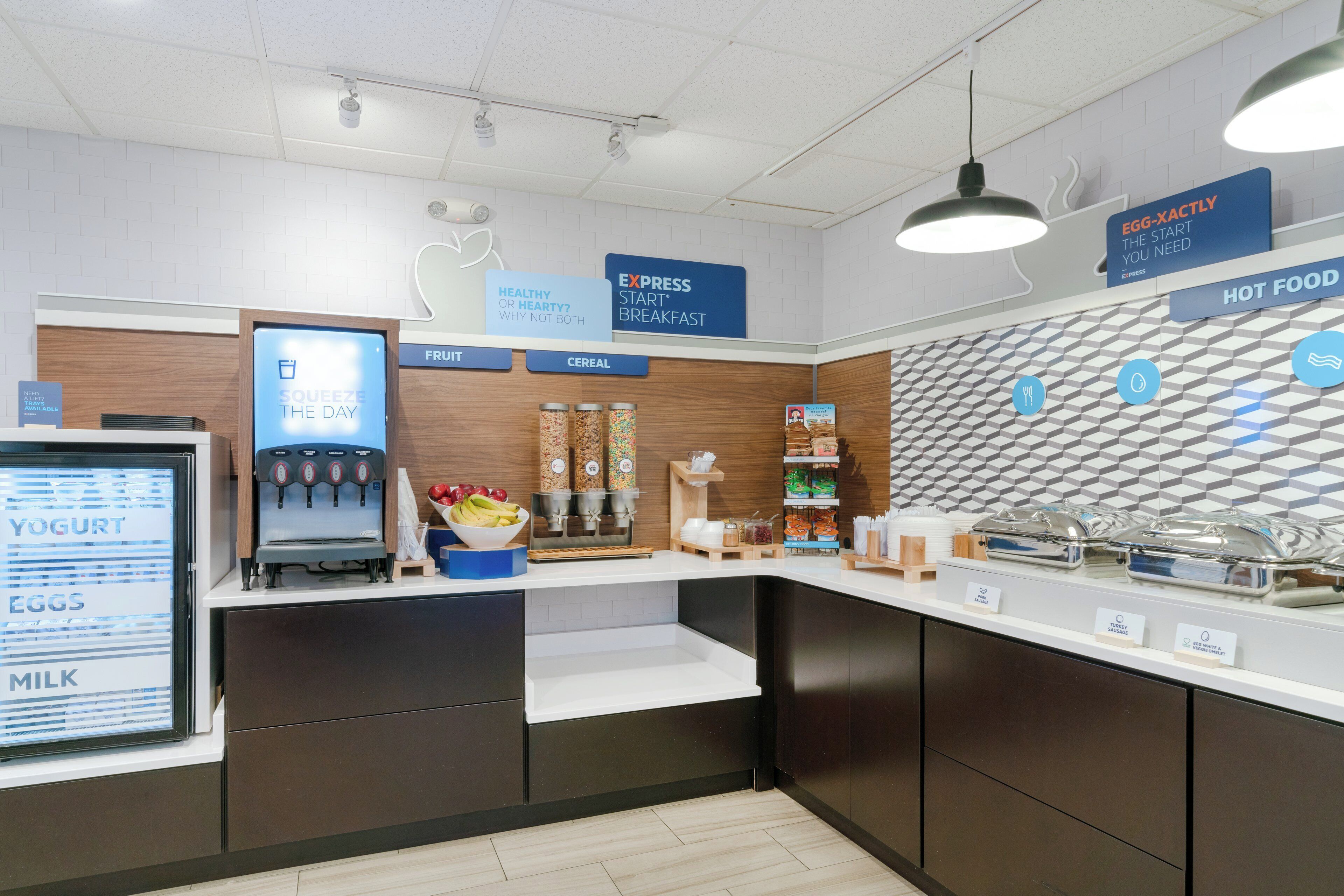 A breakfast bar with a yogurt machine, cereal, and hot food options.