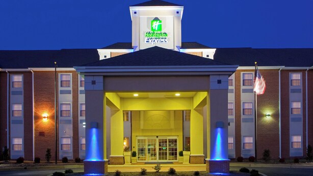 A Holiday Inn Express hotel with a central entrance, two flagpoles, and a well-lit facade.