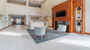 A spacious living area with a fireplace, a television, and a seating area with two chairs.