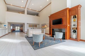 A spacious living area with a fireplace, a television, and a seating area with two chairs.