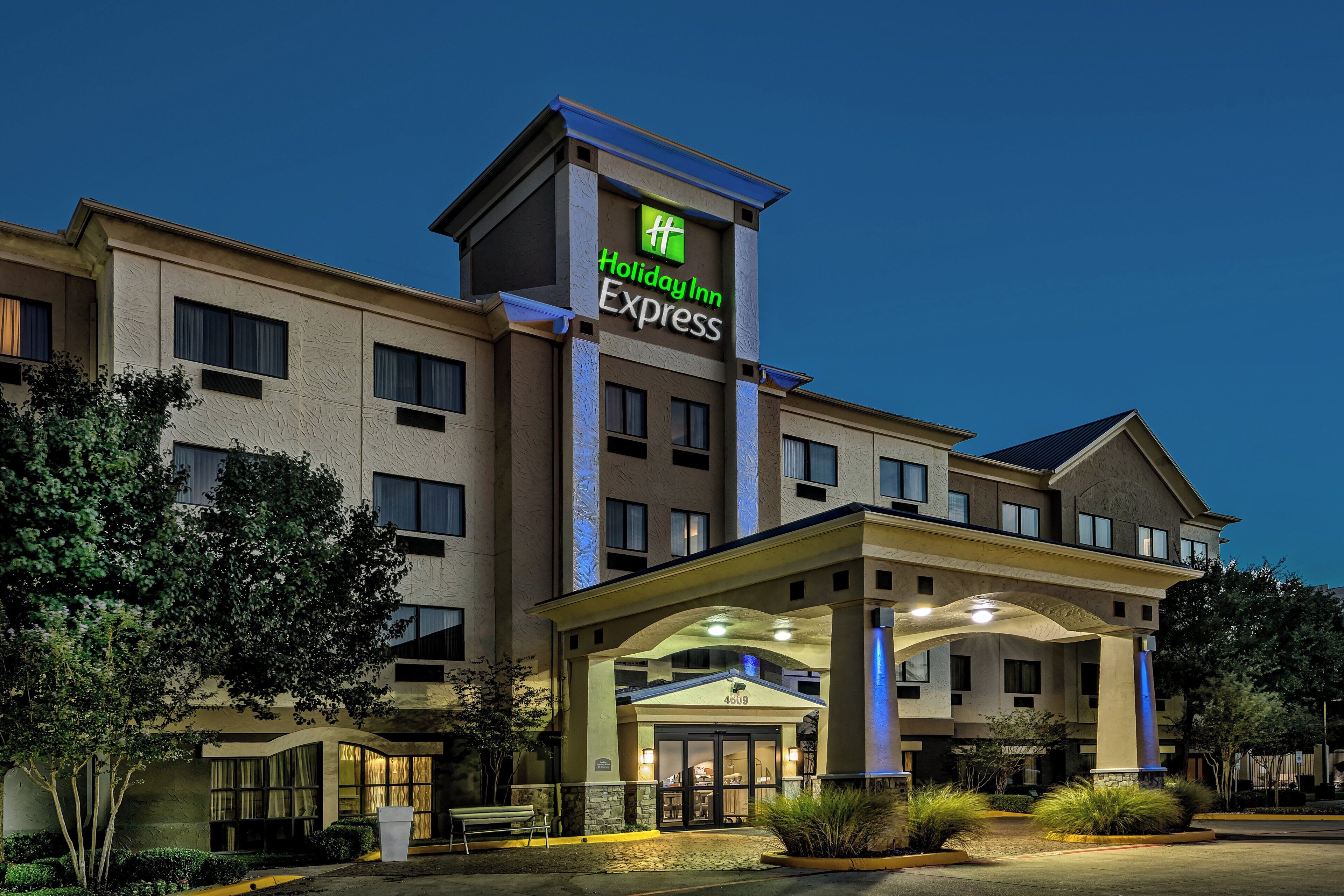 Un hotel Holiday Inn Express con fachada moderna, un acceso cubierto y un exterior bien iluminado.