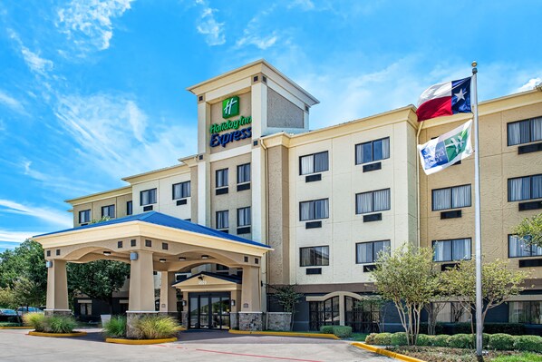 Un hôtel Holiday Inn Express doté d’une entrée couverte, de plusieurs étages et d’un mât sur lequel flottent des drapeaux.
