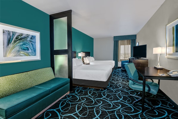 Une chambre d’hôtel avec un lit, un canapé, un bureau et une télévision.