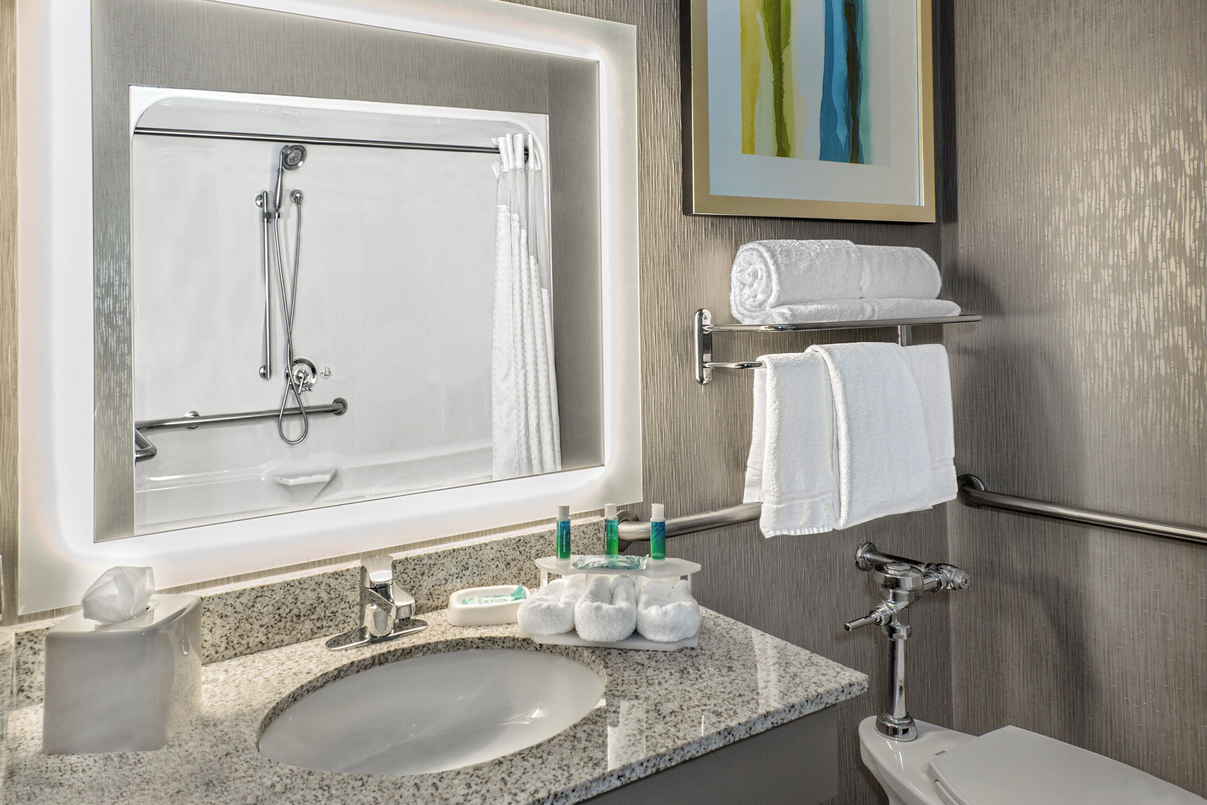 A bathroom with a sink, mirror, towel rack, and toiletries.