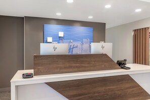 A reception desk with a modern design, featuring a wooden accent and a digital display above. - Holiday Inn Express North Conway by IHG (North Conway)