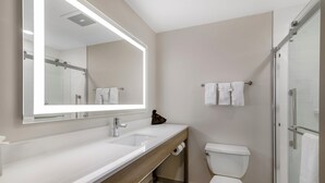 Un baño moderno con un espejo grande, un lavabo, un inodoro y una zona de ducha.