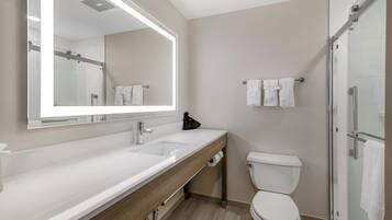 A modern bathroom with a large mirror, a sink, a toilet, and a shower area.