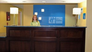 Hotellin vastaanottotiski, jonka taustalla on sininen seinä, jossa n äkyy Holiday Inn Express -logon lisäksi nimikyltti ja kyltti, jossa on ilmoitettu sisään- ja uloskirjautumisajat.