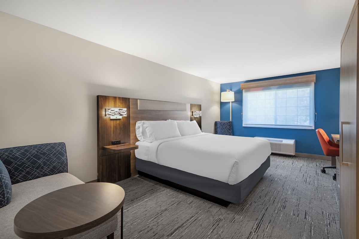 Een hotelkamer met een bed, een bureau, een stoel, een lamp en een raam.