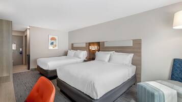 A hotel room with a large bed, a smaller bed, a desk, and a chair.