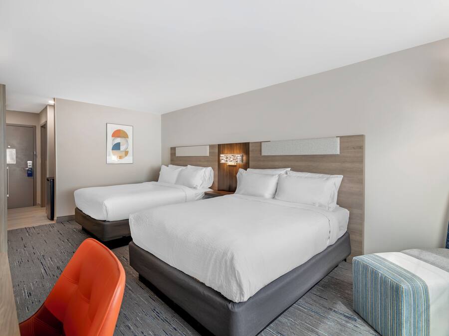 Een hotelkamer met een groot bed, een kleiner bed, een bureau en een stoel.