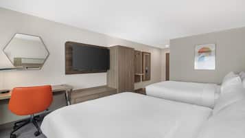 A hotel room with two beds, a desk, a chair, a TV, and a wardrobe.