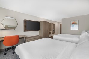 Habitación de hotel con dos camas, un escritorio, una silla, un televisor y un armario.