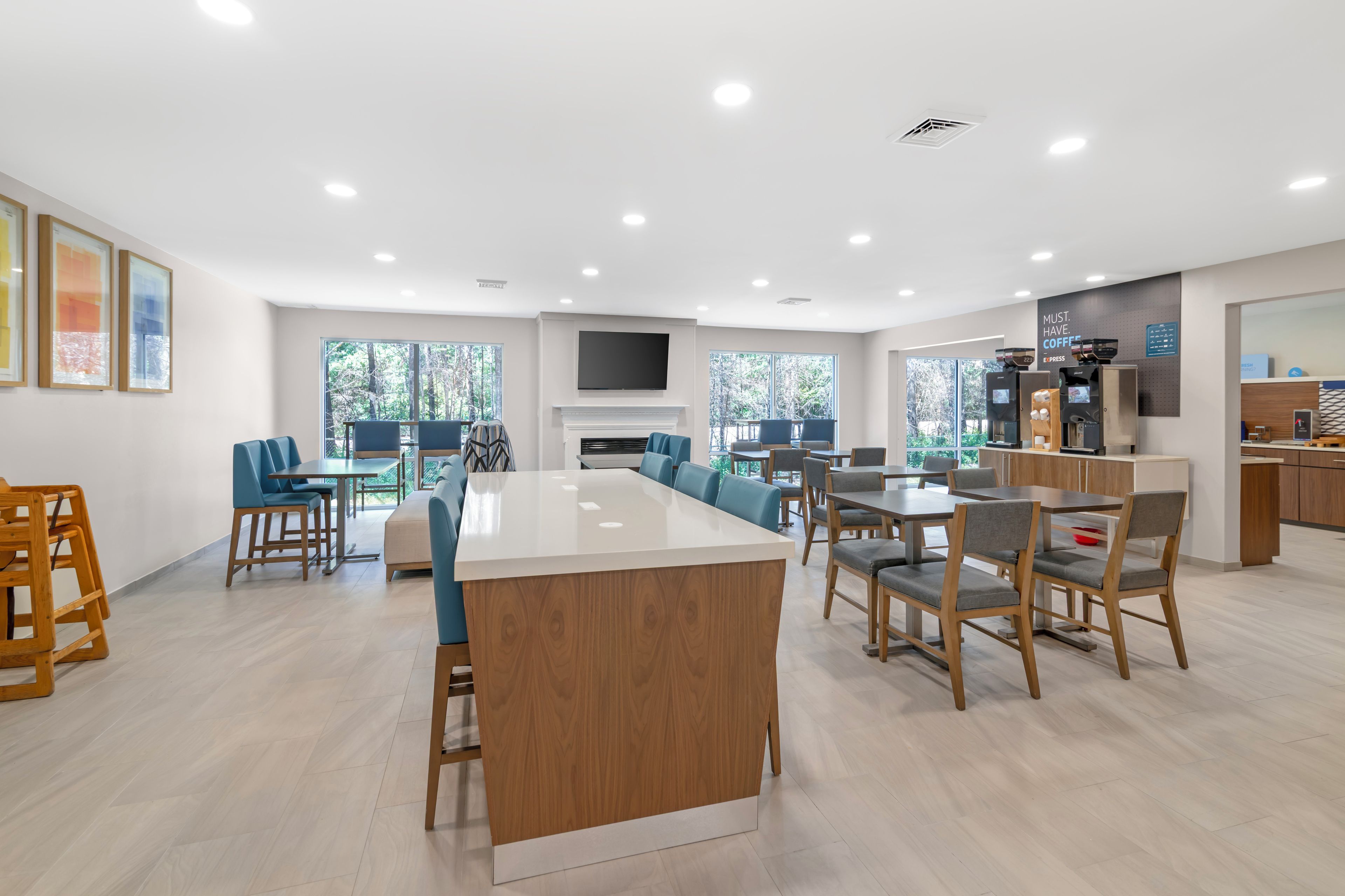 A spacious kitchen with a central island, dining area with chairs, and a coffee station.