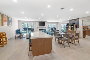 Une cuisine spacieuse dotée d’un îlot central, d’un coin repas avec des chaises et d’un espace dédié à la préparation du café.