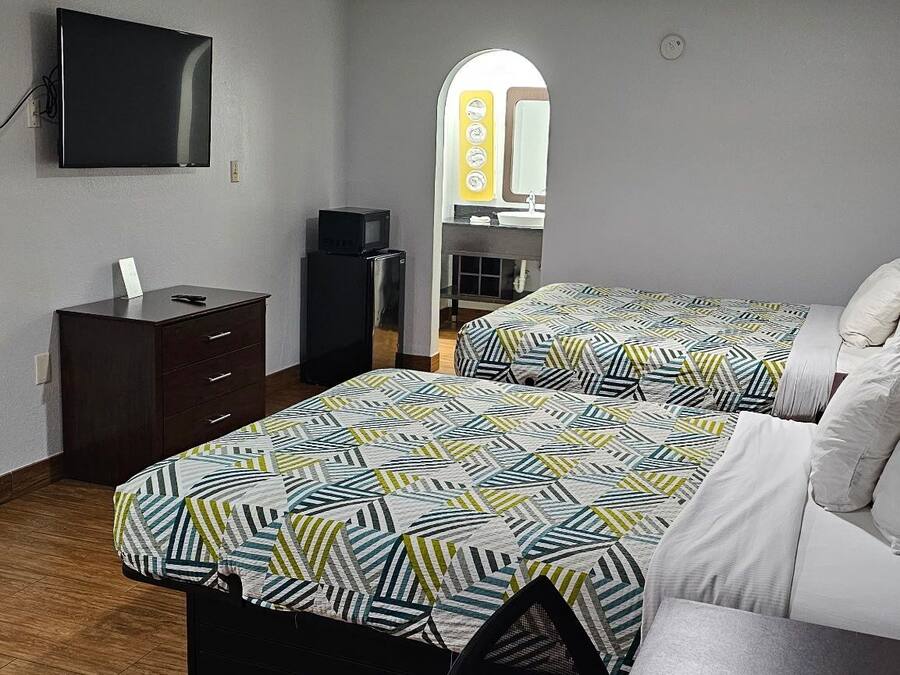 Een hotelkamer met twee bedden, een televisie, een bureau en een spiegel.