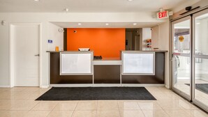A reception area with a counter, two cabinets, an orange wall, and an exit sign.