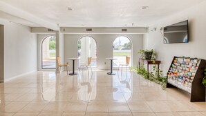 A spacious lobby with a tiled floor, three arch-shaped windows, and a reception desk with a magazine rack.