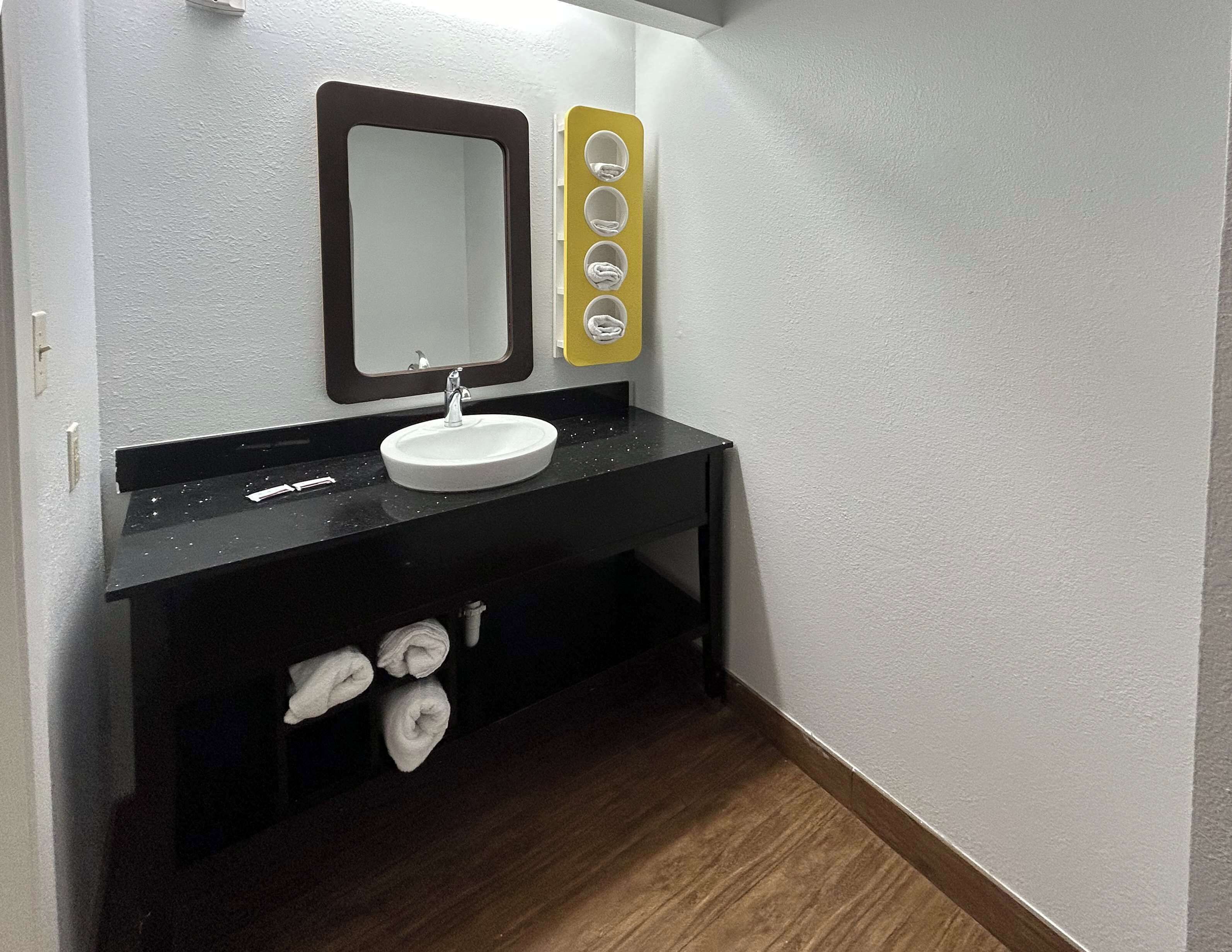 A bathroom with a white sink, a mirror, and a towel rack.