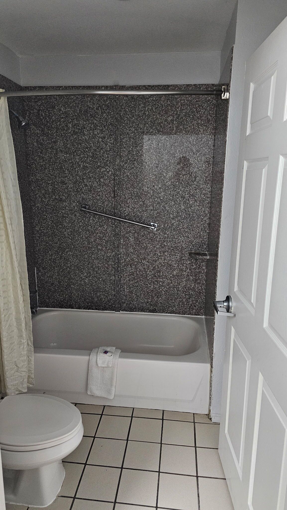 Un baño con bañera, inodoro y piso de baldosas.