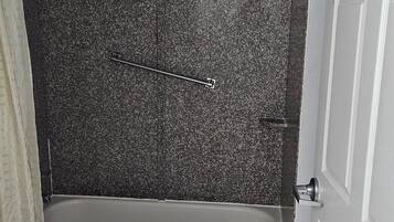 Un baño con bañera, inodoro y piso de baldosas.