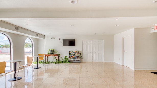 A spacious lobby with a tiled floor, a reception desk, and a television mounted on the wall.
