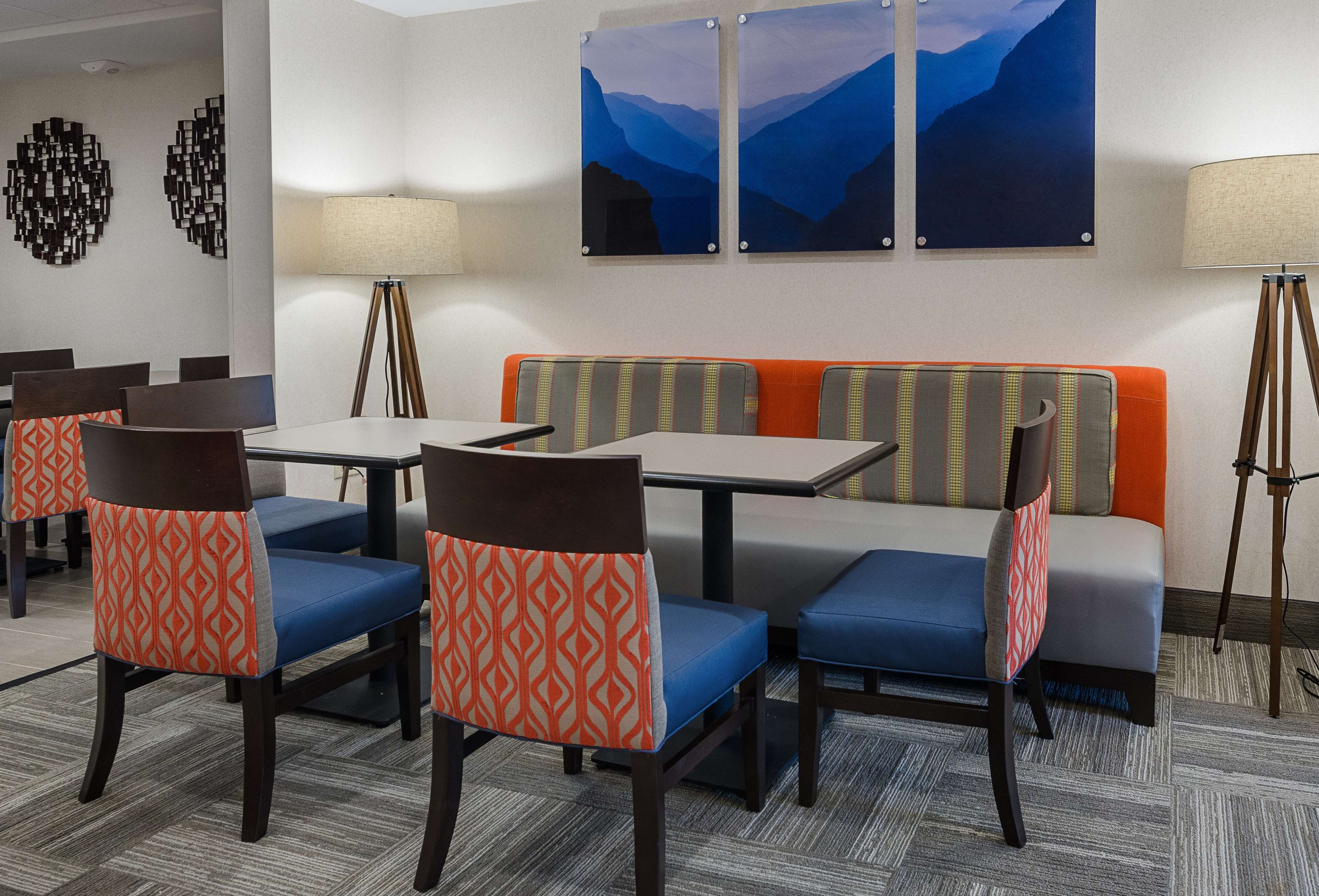 A hotel room with a dining area featuring tables and chairs, a sofa, and two wall-mounted lamps.
