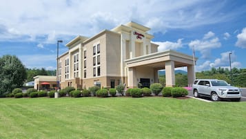A Hampton Inn hotel with a modern facade, a covered entrance, and a parking lot.