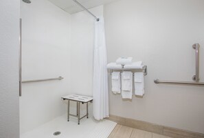 A bathroom with a shower, grab bars, a small table, and a towel rack with towels. - Holiday Inn Express & Suites Alcoa (Knoxville Airport) by IHG (Alcoa)
