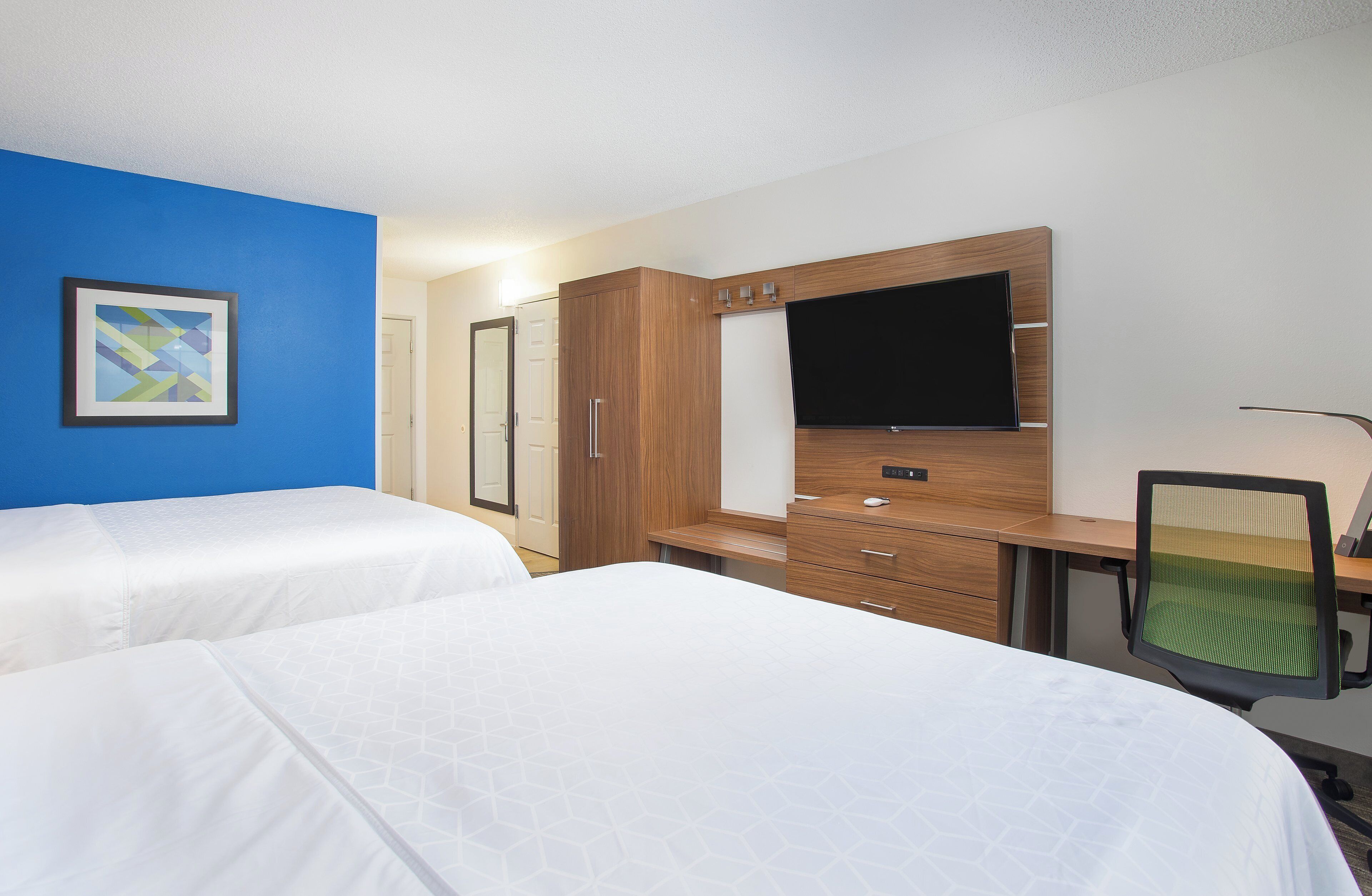 Une chambre d’hôtel avec deux lits, une télévision, un bureau et une chaise.