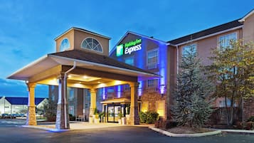 A Holiday Inn Express hotel with a covered entrance, stone pillars, and a parking lot.